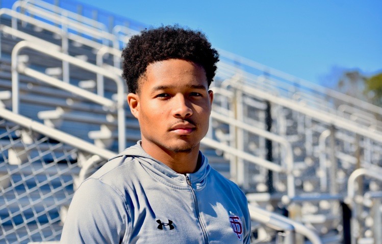 A sports fan in costume holds a protest sign against the playoff committee.